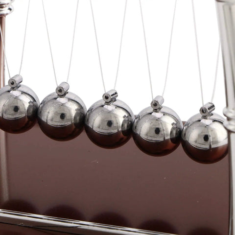 Close-up view of the Newton Cradle Desk Toy With Classic Pendulums And Gentle Clinking showing silver balance balls on a wooden base.