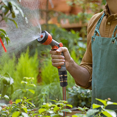Man using Three Quarter Inch Garden Hose Quick Connectors Kit with aluminum fittings for garden watering, visible spray.