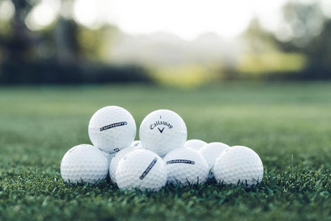 Pile of Supersoft Golf Balls 2023 White With Hyper Elastic Soft Fast Core on green grass, highlighting ball design and texture