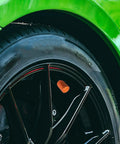 Close-up of a tire with 5 Piece Aluminum Tire Valve Stem Cap Set in orange anodized finish on a car wheel.