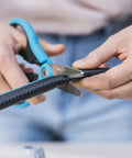 Person using scissors to cut black hose for installation with Five Eighth Inch Hose End Repair Kit for Garden Hose Fittings, Leak Repair Set