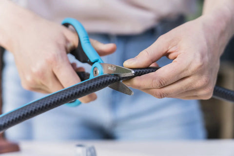 Person using scissors to cut black hose for installation with Five Eighth Inch Hose End Repair Kit for Garden Hose Fittings, Leak Repair Set