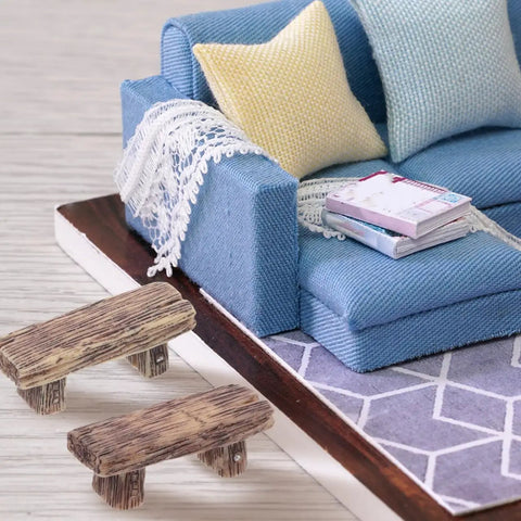 4 Pack Miniature Resin Park Benches for Fairy Gardens and Dollhouses placed near a blue fabric sofa with pillows and books
