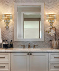 Wall-mounted gold crystal wall sconce with beveled prisms and stainless steel in modern bathroom setup