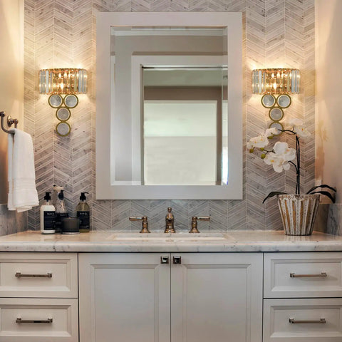 Wall-mounted gold crystal wall sconce with beveled prisms and stainless steel in modern bathroom setup