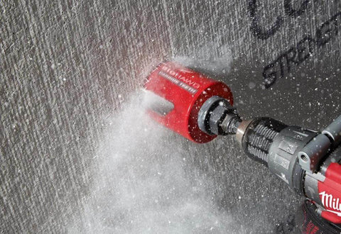Milwaukee 4-1/4 in Big Hawg carbide hole saw attached to a drill drilling into concrete.