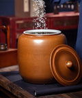 Hella Durable Ceramic Cereal And Rice Dispenser With Seamless Airtight Lid, brown ceramic jar with lid and grains pouring inside