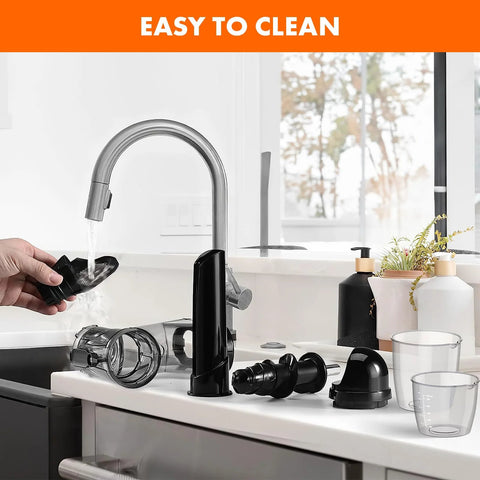 Masticating juicer attachment for KitchenAid stand mixer; black plastic parts with clear chamber on counter.