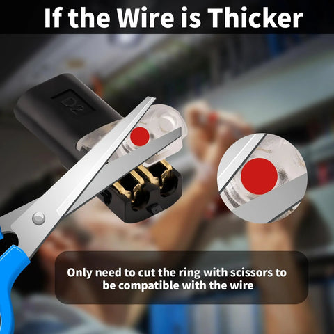 Front view of a two-pin quick-splice wire connector with black housing and gold contacts, being cut by scissors.