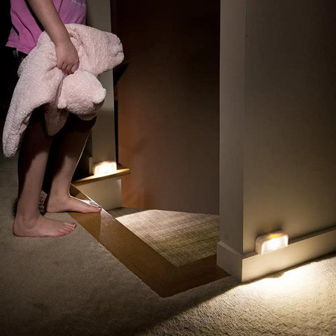 Wireless Motion Sensing LED Night Lights Six Pack Tiny Stick Anywhere White Battery Powered Auto On When Motion Is Detected In Darkness Great For Hallways Closets And Stairs illuminating a dark staircase.
