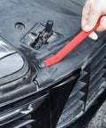 Using a red nylon tool from Snag These Dope 5 Piece Nylon Auto Trim Removal Tools For Your Ride to pry a car panel.
