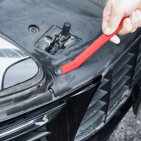 Using a red nylon tool from Snag These Dope 5 Piece Nylon Auto Trim Removal Tools For Your Ride to pry a car panel.