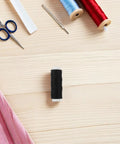Sewing tools on table with black thread spool, scissors, and fabric.