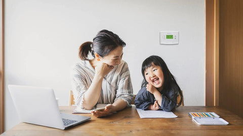 Woman with child in room featuring 5 2 Day Programmable Thermostat With Easy Weekday Weekend Scheduling Precise Temperature Control on wall.