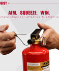 Person demonstrating usage of ABC Fire Extinguisher For Home And Vehicle, Two And A Half Pound Compact Fire Extinguisher For Kitchen, Garage, Truck, Car, Boat, Pro Safety Grade, Red Two Pack with pin removal and nozzle aiming.