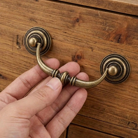 12 Pack Antique Bronze Drop Bail Pulls For Cabinets And Dressers, 3.5 Inch Center To Center, being attached to a wooden drawer.