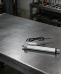 12V Electric Linear Actuator With Straight Push Pull Rod For Heavy Duty Industrial Automation And Sofa Lifts IP65 Waterproof, shown on metal surface.