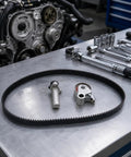 Premium Heavy Duty Timing Belt Kit With Tensioner Roller And Idler Pulleys For Lexus IS300 SC300 GS300 And Toyota Supra 3 0L 2JZ Matched Oem Specs To Restore Peak Power While Keeping Your Ride Cruising Smooth As Silk Until The Next Fix. Timing belt, tensioner, and idler pulleys on a workbench.