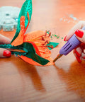 Using bedazzler kit with rhinestones and hot fix gems craft applicator to decorate a fabric flower with precision.