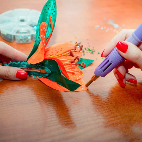Using bedazzler kit with rhinestones and hot fix gems craft applicator to decorate a fabric flower with precision.