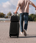 Two Piece Hardside Luggage Set With 20 Inch Carry On Spinner Suitcase And 14 Inch Stackable Travel Handbag ABS Durable Lightweight Trolley For 1 To 4 Day Trips TSA Friendly Jet Black being carried by a person walking outdoors