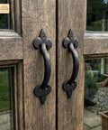 Old School Medieval Rustic Cast Iron Door Pull With Fleur De Lis Handle And Compact Grip, 7 1/8 Inch Decorative Hardware For Cabinets, Wardrobes And Garden Sheds, Sturdy Classic Farmhouse Style installed on wooden doors.