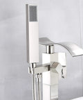 Close-up of floor mounted tub filler faucet with handheld sprayer and waterfall spout in brushed nickel finish.