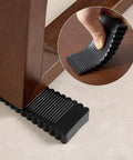Rock Solid Black Rubber Wedge Shims For Furniture Leveling Hella Sturdy Anti Slip Wobble Pads placed under a table leg.