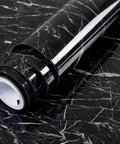 Self Adhesive Marble Countertop Wallpaper Peel And Stick Black Marble Design With Grid Back For Easy Cutting 18 Inch By 394 Inch Roll Durable DIY Friendly Kitchen Counter Cover roll on black marble surface.