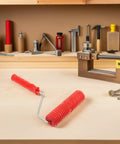 Knockout 2 Piece Wood Grain Texture Paint Roller Pair Featuring Rock Solid Grip Handle For Quick Drywall Mud Work And Real Deal Fake Timber Finish Results That Truly Stand Out resting on a workbench with other tools.
