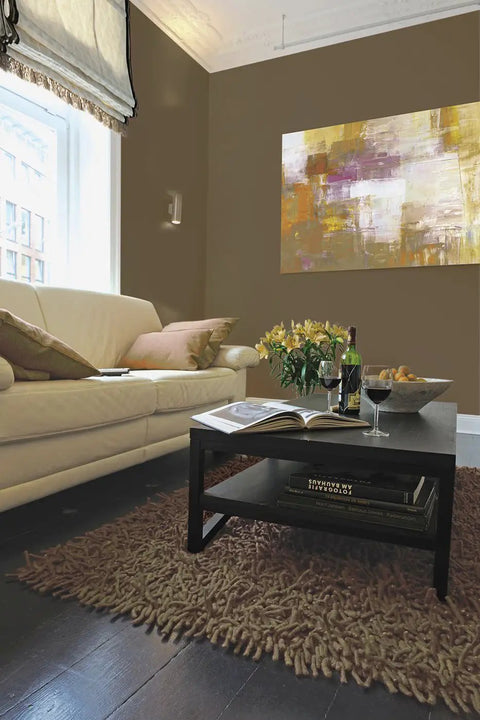 Living room with brown walls painted in Interior Paint And Primer In One Satin Finish 1 Gallon, artwork and sofa visible.