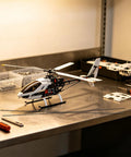 Workbench with tools and RC helicopter next to Ten Pack Carbon Fiber Wing Spar Poles for RC Planes Heavy Duty High Strength Structural Rods.