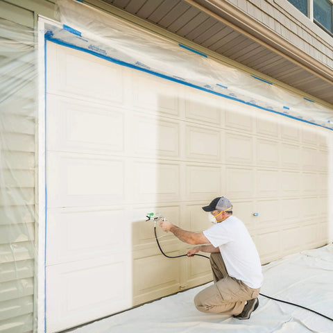 Person using a Heavy Duty Mobile Airless Paint And Stain Sprayer Cart to paint a garage door for smooth finishes.