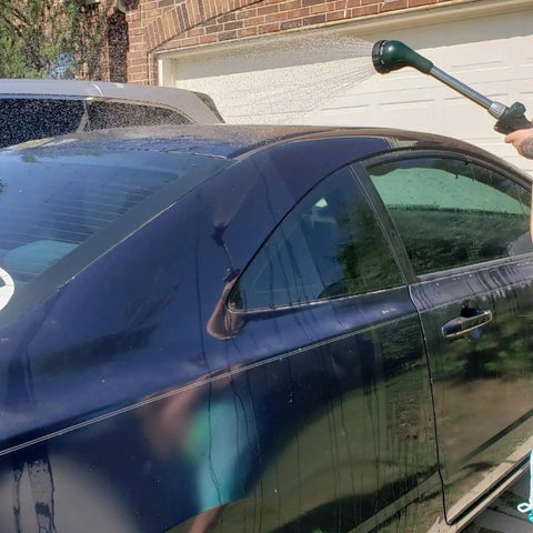 Using Watering Wand 16 Inch Heavy Duty Garden Tool With 8 Spray Patterns on dark blue car, showing long reach.