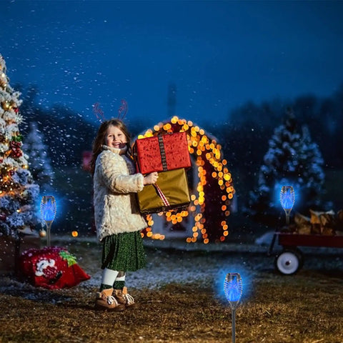 Child with festive gifts in snow with Blue Solar Torch Lights With Flickering Flames, 12 Pack Outdoor LED Tiki Torches For Yard And Garden