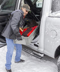 Person loading Heavy Duty Plastic Storage Tote With Straight Wall Design 48 Inch By 15 Inch By 7.5 Inch into vehicle in snow