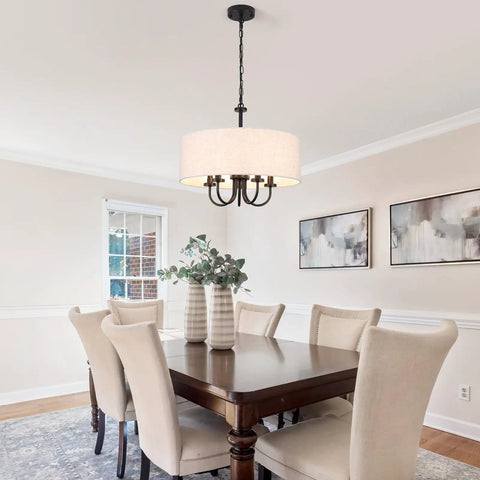 Dining room with modern chandelier above table, surrounded by upholstered chairs, artwork on wall.