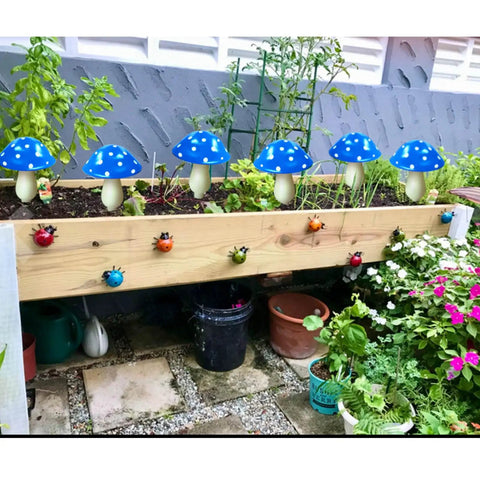 Six Pack Blue Solar Garden Mushroom Stake Lights With Eight Lighting Modes For Outdoor Yard Decor Solar Powered Waterproof Garden Ornaments in a garden bed with plants and flowers.