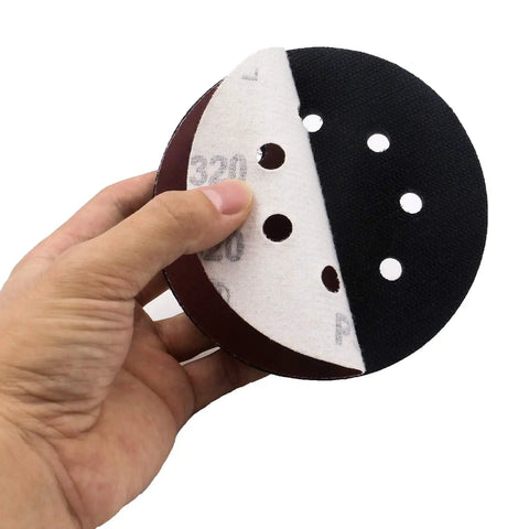 Five Pack 5 Inch Soft Density Interface Pads With Eight Hole Design, Hook And Loop Backing For Easy Swapping held in hand