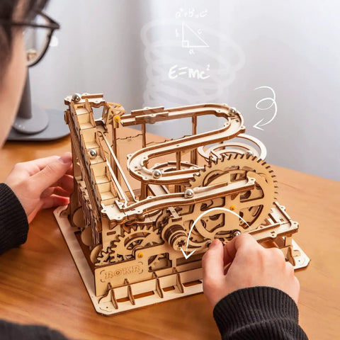 Hands adjusting Totally 3D Wooden Marble Run Puzzle Kit With Gear Powered Roller Coaster Track For Adults No Glue Needed Hands On DIY Mechanical Model Gift Idea With Waterwheel Lifter And Multi Level Tracks on desk