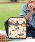 Insulated Lunch Tote Bag With Shoulder Strap for teens with cowboy print, reusable and portable, on grass with person eating.