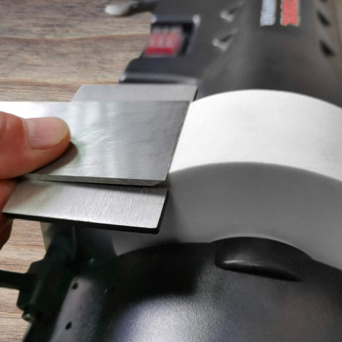Close-up of Low Speed Knife Sharpener With Wet And Dry Grinding Wheel 0.7 Amp, showing metal blade against grinding wheel.