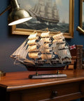 Cutty Sark 1/195 Scale Wooden Model Ship on desk with lamp, handcrafted basswood hull with fabric sails, for home decor.