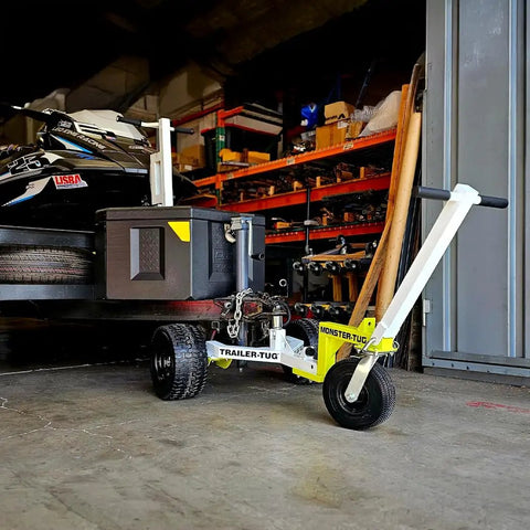 Monster Tug Off-Road Trailer Dolly Moves Boat, RV, Or Utility Trailer With Ease On Sand, Dirt, Gravel, Concrete Hard Surfaces Heavy Metal Frame Manual Mover No Motor Needed Adjustable Ball Mount For Any Tow in garage with black utility trailer.