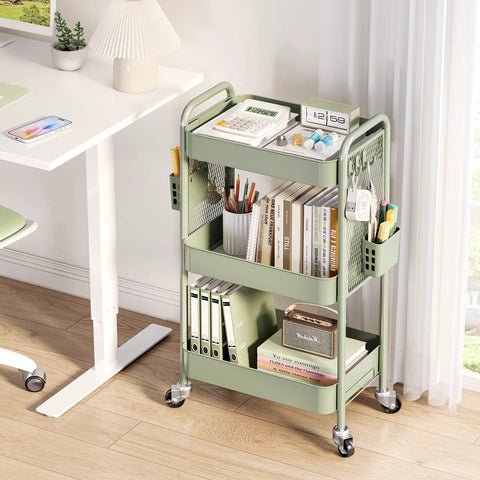 Three Tier Rolling Cart Storage Organizer with Metal Wheels Pegboard Hooks and Bins for Bathroom Kitchen Office Nursery and Craft Rooms positioned beside a desk