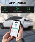 Person holding smartphone showing Tesla Level 2 EV Charger 9.6 kW app control, car charging in background, NEMA 14-50 plug visible.