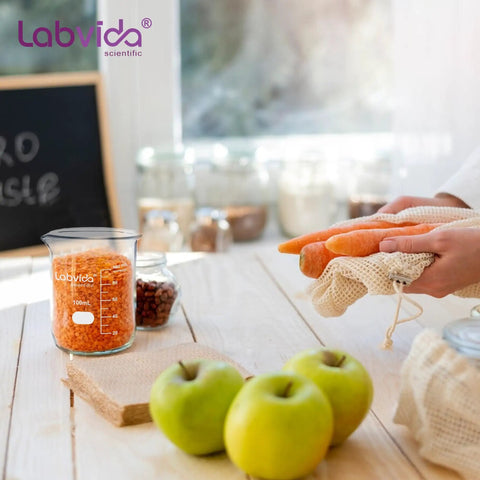 Six Size Low Form Glass Beaker Set With Printed Graduation For Accurate Measurement Includes 25Ml 50Ml 100Ml 250Ml 500Ml 1000Ml 3.3 Borosilicate Glass Lab Beakers With Large Markings on kitchen counter with apples and carrots.