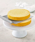 Cake Lifter With Wide Surface And Offset Handle, Stainless Steel, transferring 9-inch cake layer on marble stand.