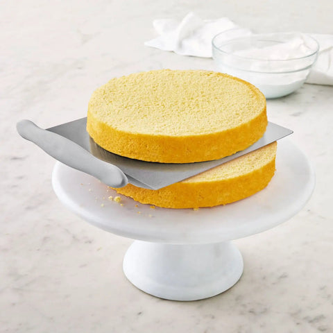 Cake Lifter With Wide Surface And Offset Handle, Stainless Steel, transferring 9-inch cake layer on marble stand.