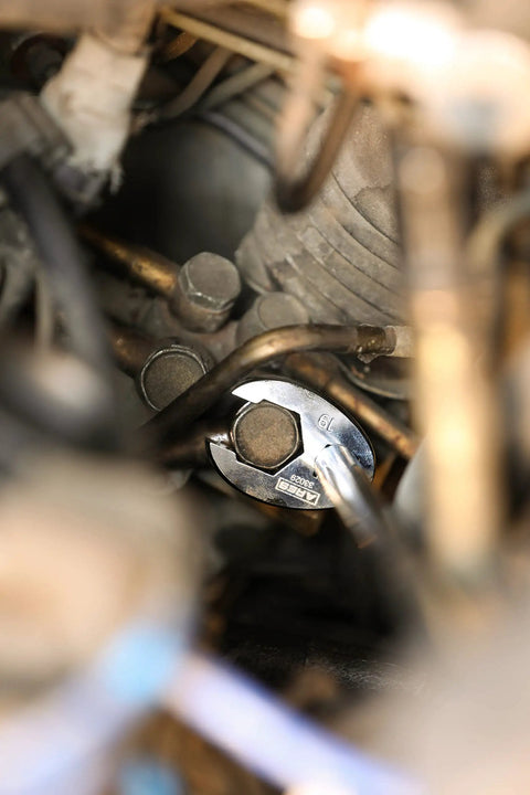 Close-up of 10-Piece Metric Flare Nut Crowfoot Wrench Set for Tight Spots gripping a fastener in a mechanical setting, 6-point head visible